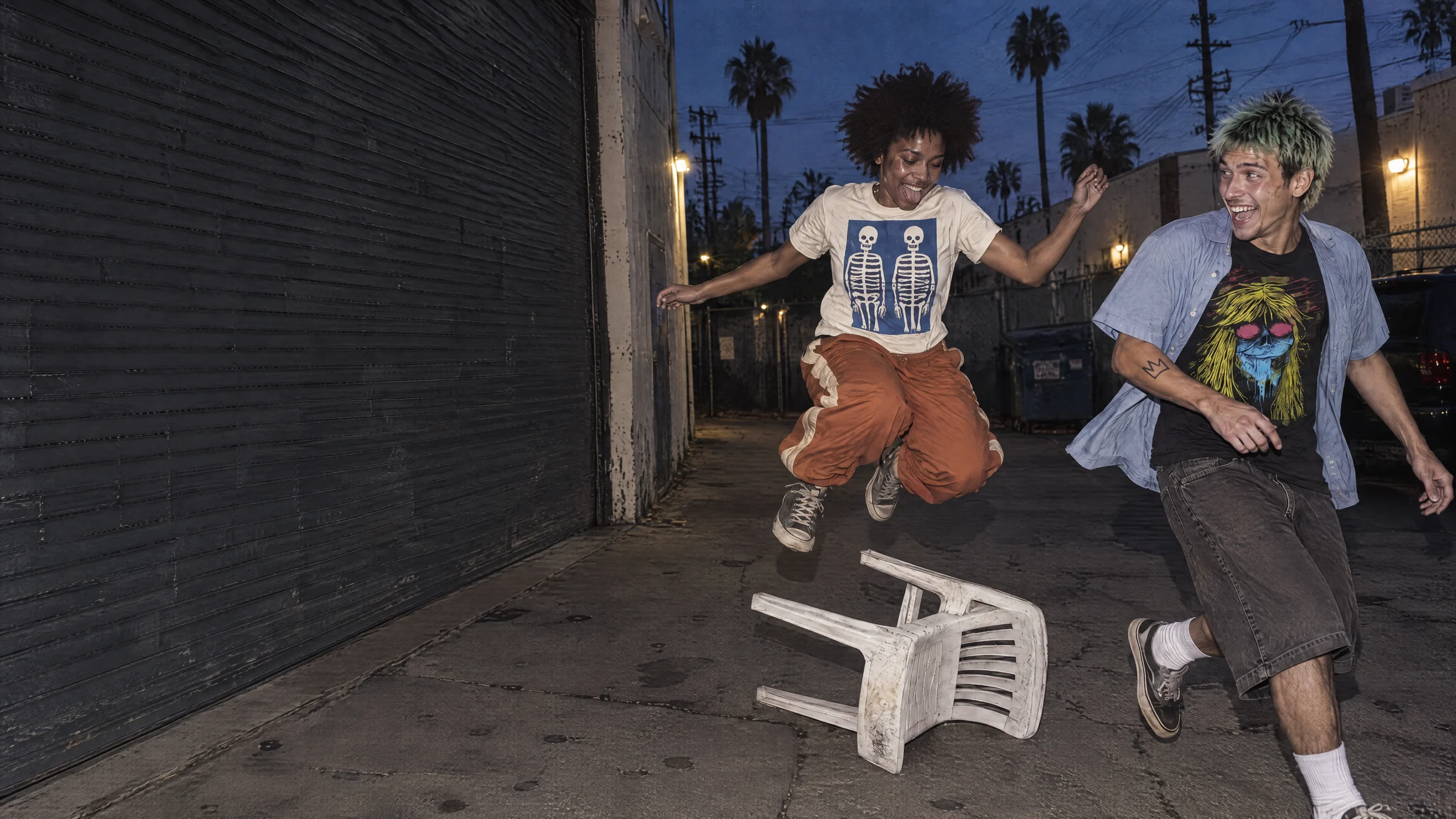 Two friends in Bone Twins and Acid Witch tees caught mid-jump outside an LA rehearsal space at dusk